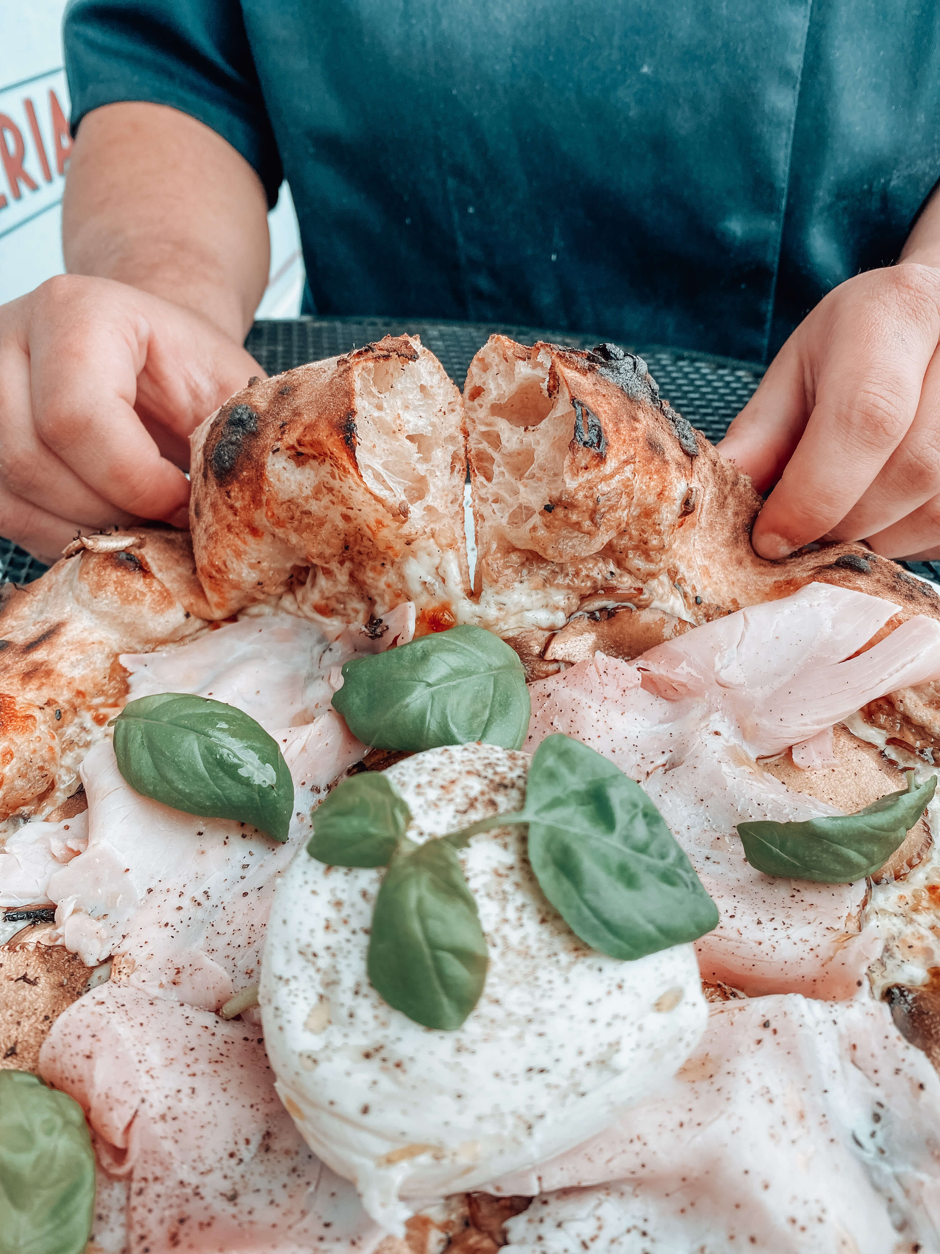Pizza garnie de mortadelle, burrata et basilic, travail de la garniture en formation pizzaïolo à Lyon